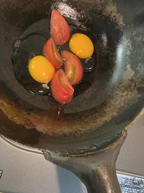 フライパンの上にくし形トマトをまん中・両脇に卵