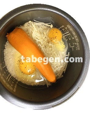 お米と水を炊飯器内釜にセットした上に、卵・えのきだけ・にんじんを入れた画像